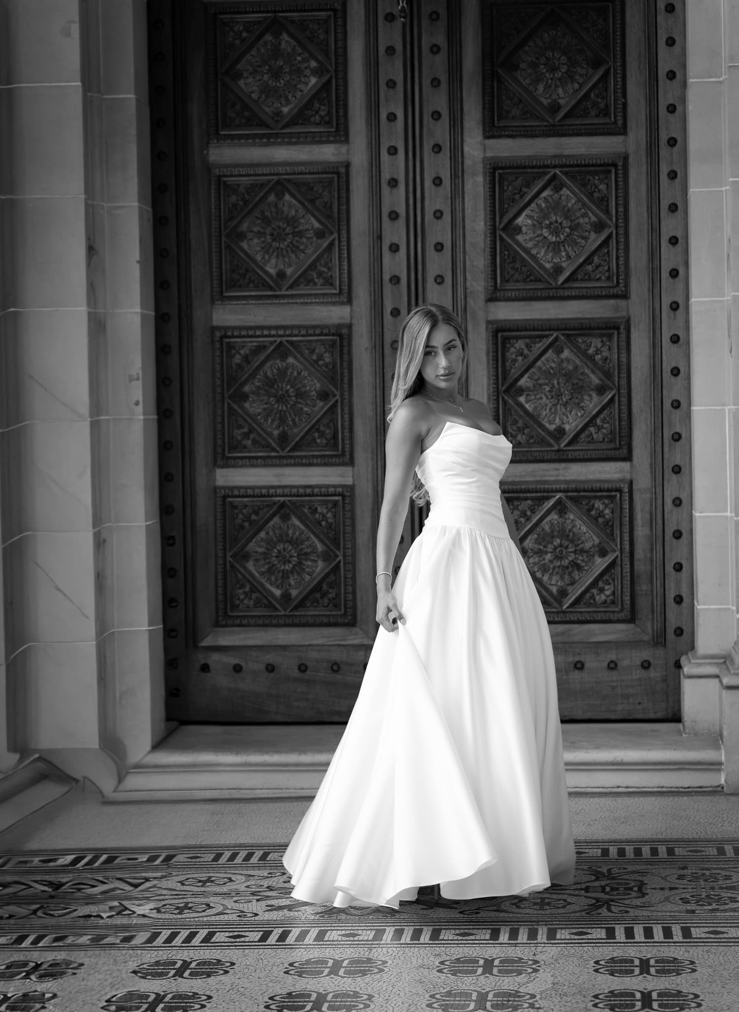 Against the carved doors, in black and white
